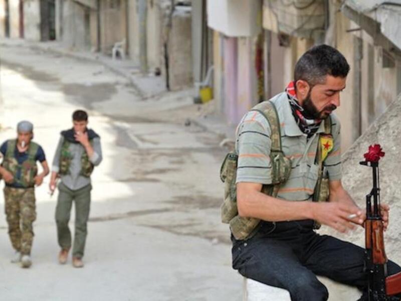 A rebel fighter of the Syrian Kurdish Popular Protection Units (YPG) has a flower in his Russian made 'AK-47' kalashnikov gun as he holds a position in the Sheikh Maqsoud neighbourhood in the Syrian city of Aleppo. AFP Photo