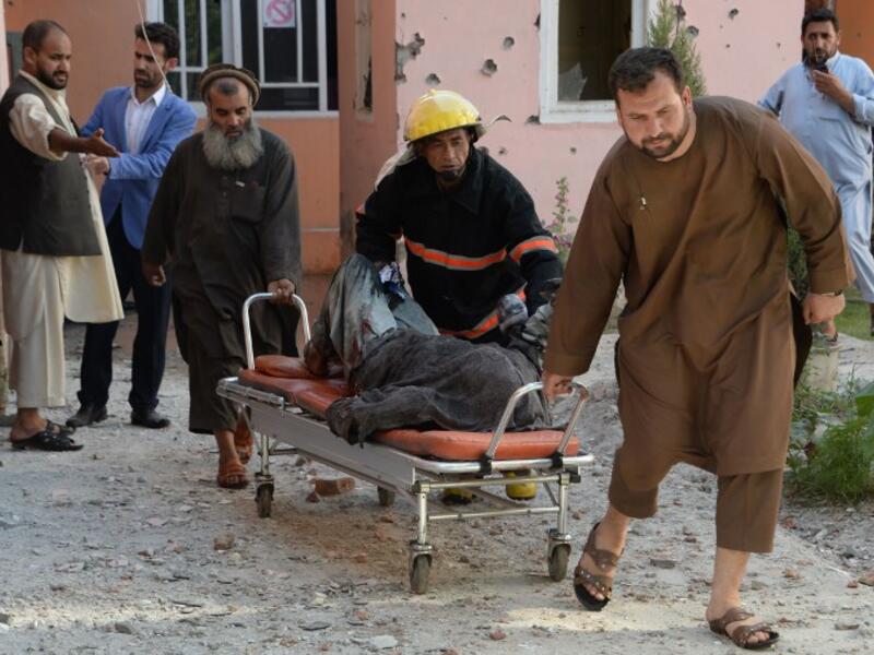 Afghan volunteers move a body from the scene of a suicide attack that targeted the national television station in Jalalabad on May 17, 2017. (AFP/Noorullah Shirzada)