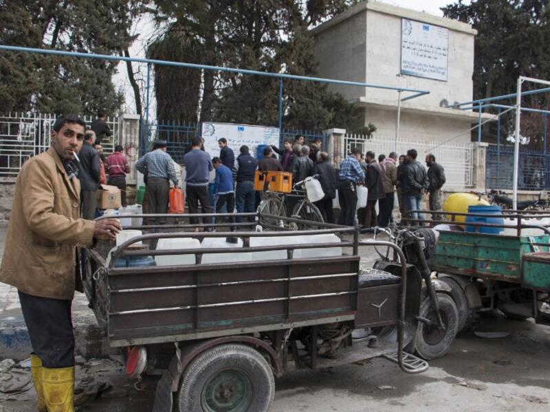 Aleppo residents line up outside to refill water cans as the ceasefire encourages people to be out in public. (AFP/Karam Al-Masri)