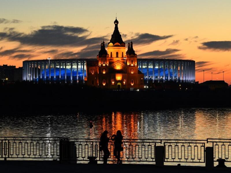 Young women stand in front of the Nizhny Novgorod stadium situated behind the cathedral of Alexandr Nevskiy in the city of Nizhny Novgorod, during the Russia 2018 World Cup on June 16, 2018. 
Johannes EISELE / AFP