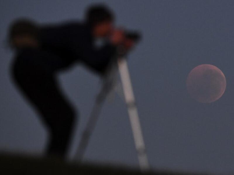 People gather to watch a "blood moon" eclipse in Melbourne on July 28, 2018. (AFP/WILLIAM WEST)