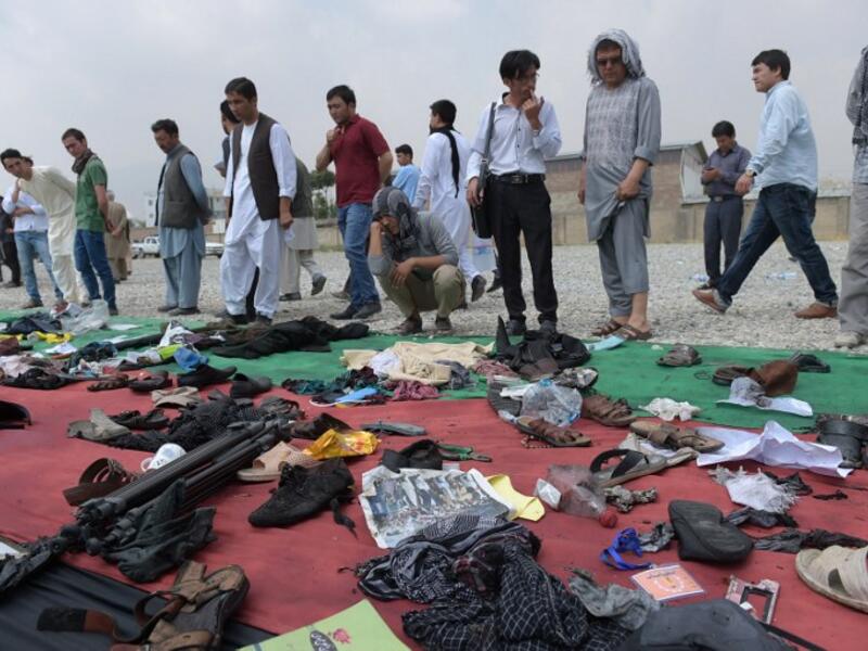 Relatives and friends inspect shoes and other belongings of those who were killed in the twin suicide attack, gathered on the ground at a mosque in Kabul on July 24, 2016. (AFP/Shah Marai) 