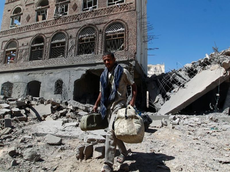 A Yemeni man carries his bags through the ruins of buildings destroyed in an air strike by the Saudi-led coalition in the capital Sanaa on October 28, 2015. (AFP/Mohammed Huwais)