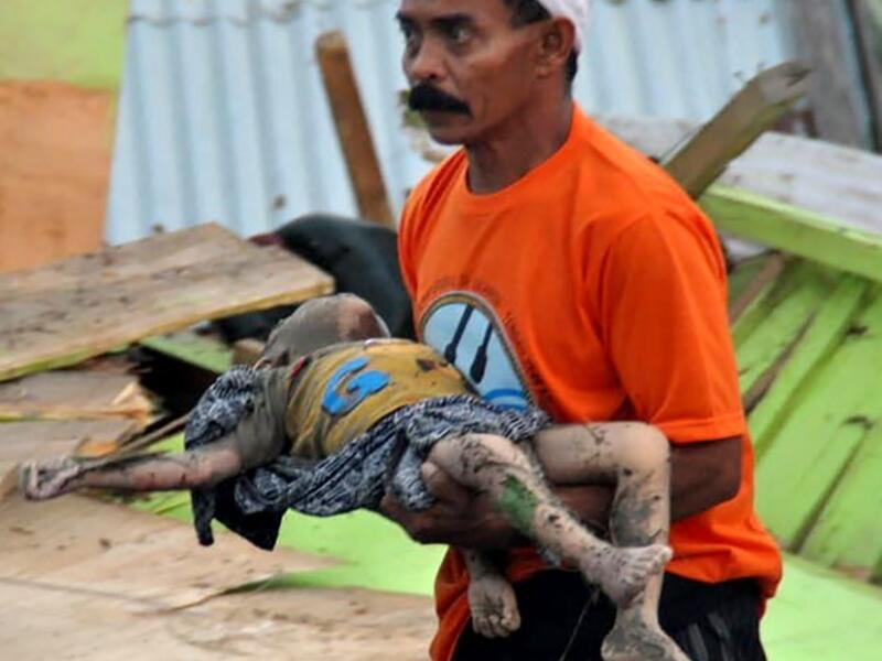A man carries the body of a child after an earthquake and tsunami hit Palu, on Sulawesi island on September 29, 2018. (MUHAMMAD RIFKI / AFP)