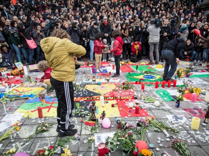 People gather to observe a minute of silence in memory of the victims of the Brussels airport and metro bombings, on the Place de la Bourse in central Brussels, on March 23, 2016, a day after the triple blasts killed some 30 people and left around 250 injured. (AFP/Aurore Belot)