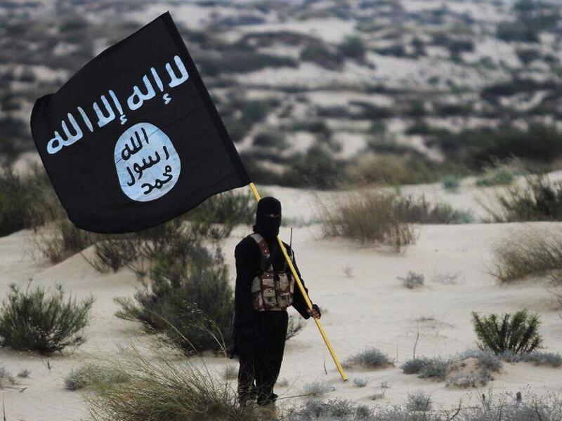 A militant carries a Daesh flag. (Screenshot)