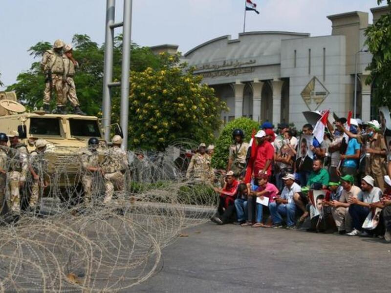  Supporters of the Muslim Brotherhood and ousted Egyptian president Mohamed Morsi raise pictures of the toppled leader in front of Army soldiers blocking Salah Salem highway in Cairo, on July 19, 2013.  AFP PHOTO /MARWAN NAAMANI