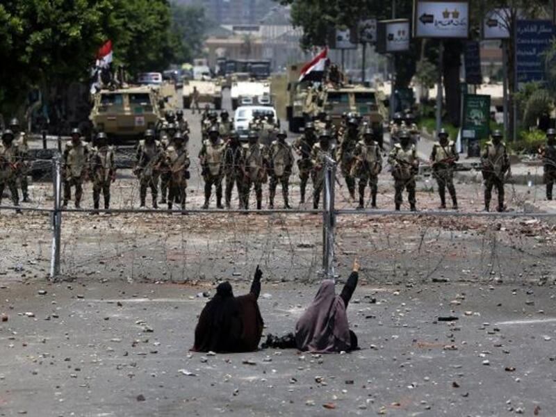 Egyptian supporters of deposed president Mohamed Morsi sit in front of barbed wire fencing that blocks the access to the headquarters of the Republican Guard in Cairo on July 8, 2013. (AFP/PHOTO / MAHMUD HAMS)