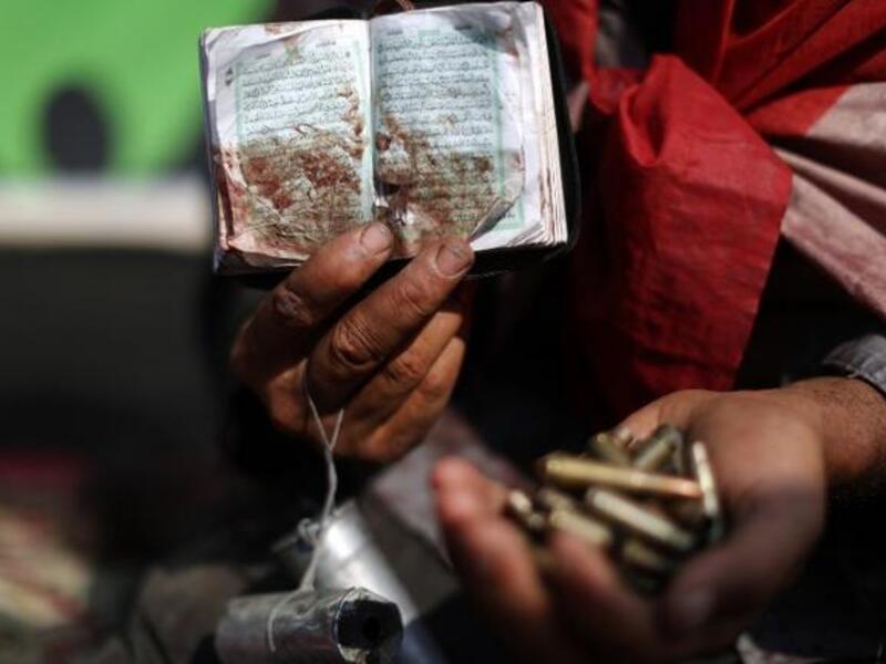 An Egyptian supporter of deposed president Mohamed Morsi holds a copy of the Koran stained with blood and empty casing as he attends a rally in support of the former Islamist leader (AFP)