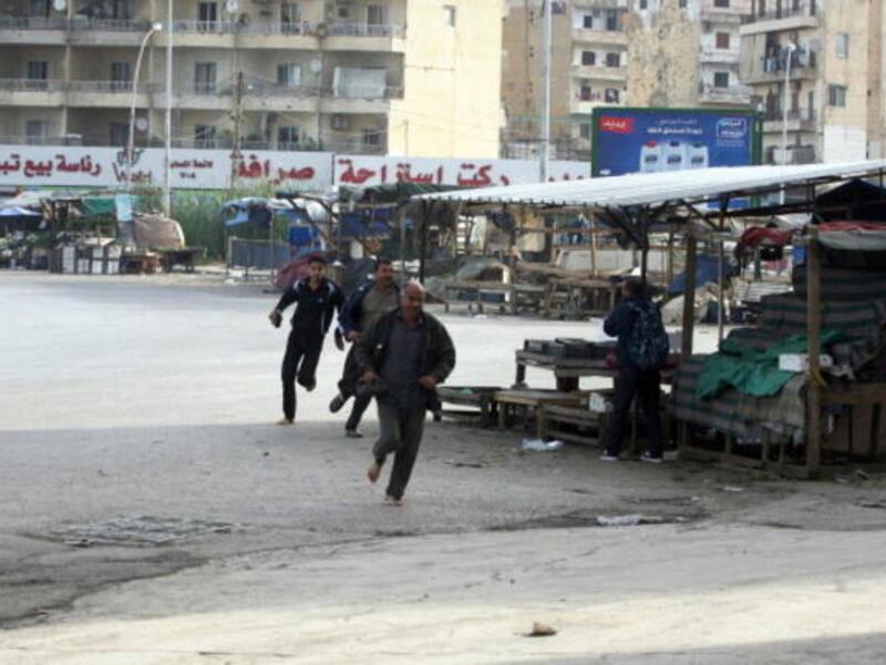 People run for cover from sniper fire in the Lebanese northern coastal city of Tripoli on December 1, 2013. [AFP]