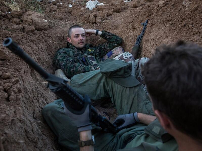A 21-year-old Briton and a 23-year-old American nicknamed 'Hewal Sores' and 'Hewal Agir' stand guard at a post outside Tal Tamr on April 19, 2015. Working alongside YPG troops who speak little English, foreign fighters are often placed together in troops.
