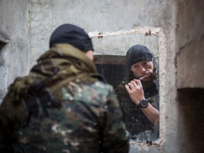 A 33-year old from New Zealand, nick-named by Kurdish fighters as ‘Hewal Welat,’ brushes his teeth on April 17, 2015 just outside Tal Tamr.