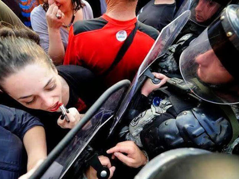 applying lipstick using riot police shield 'mirror'