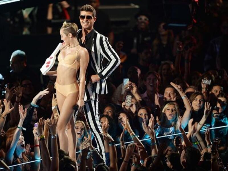 ثم تراقصت سايرس مع ثيكي أثناء أدائهما لأغنية " Blurred Lines" بحركات تشبه إلى حد بعيد حركات راقصات التعري، بالإضافة إلى حركات لسانها المليئة بالإيحاءات الجنسية