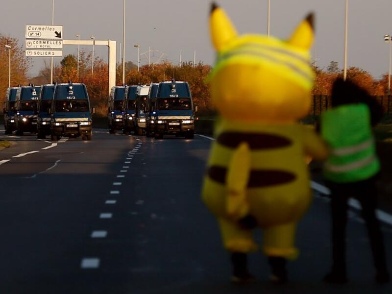 People and a mascot of Pikachu stand in front of gendarme's trucks on Caen's circular road on November 18, 2018 in Caen, northwestern France.
CHARLY TRIBALLEAU / AFP
