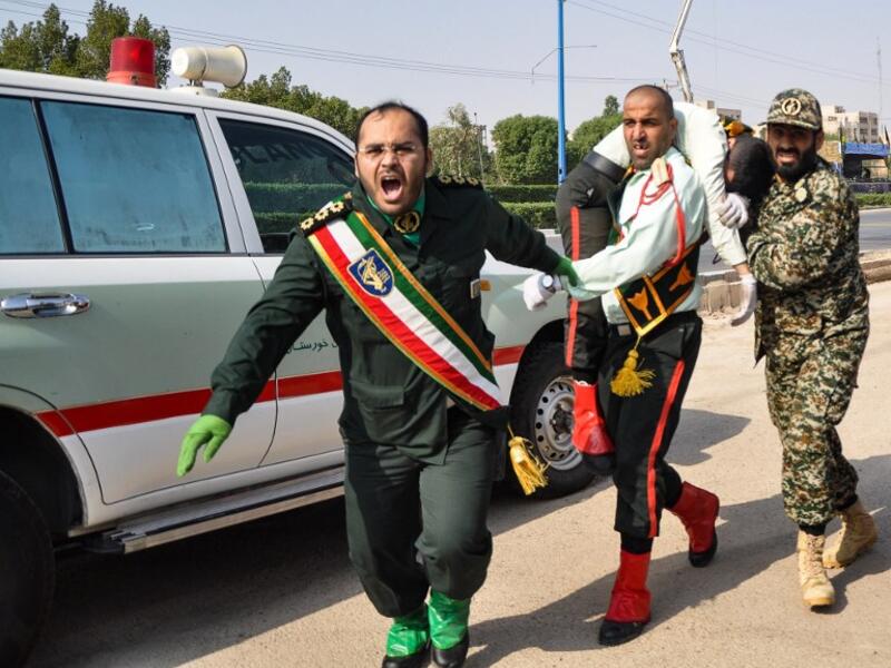 An Iranian soldier carrying an ijured comrade at the scene of an attack on a military parade. (BEHRAD GHASEMI / ISNA / AFP)