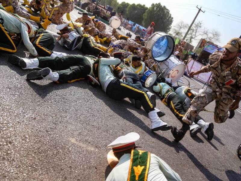 This picture taken on September 22, 2018 in the southwestern Iranian city of Ahvaz shows a soldier running past injured comrades lying on the ground at the scene of an attack on a military parade. (MORTEZA JABERIAN / ISNA / AFP)