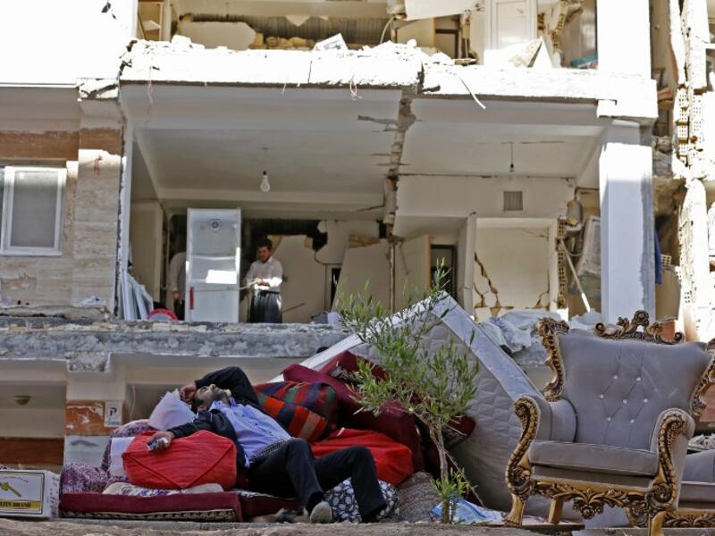 A man rests in the ruins of his home in Kermanshah province following Sunday's deadly earthquake (Atta Kenare/AFP)