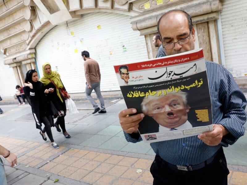 An Iranian man reads a copy of the daily newspaper 'Omid Javan' bearing a picture of U.S. President Donald Trump with a headline that reads in Persian "Crazy Trump and logical JCPOA (Joint Comprehensive Plan of Action)" (AFP)
