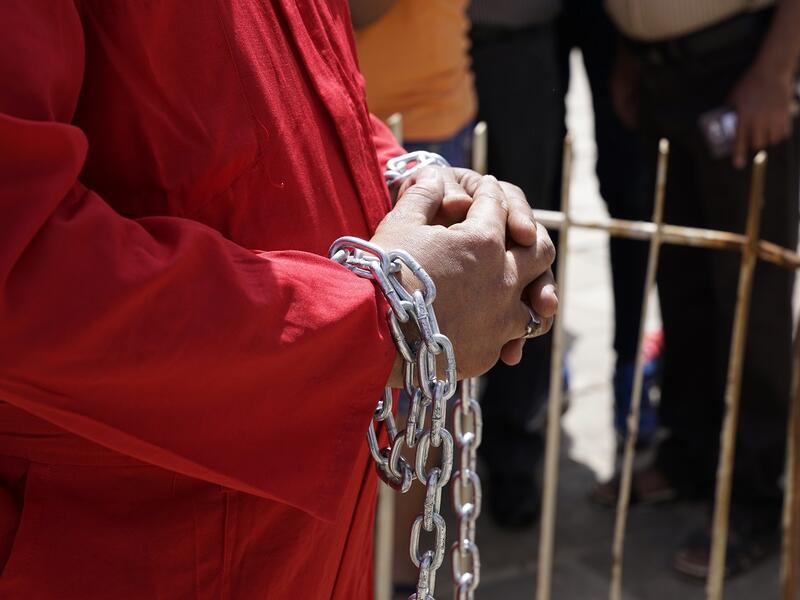 A man in an orange prison jumpsuit in chains protest Iraq's raping law. 
Baghdad's Woman Association