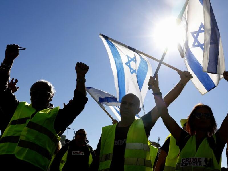 Israeli protesters wearing a yellow vest carry national flags during demonstrations against the rising cost of living on December 14, 2018, in the Israeli coastal city of Tel Aviv. 
JACK GUEZ / AFP