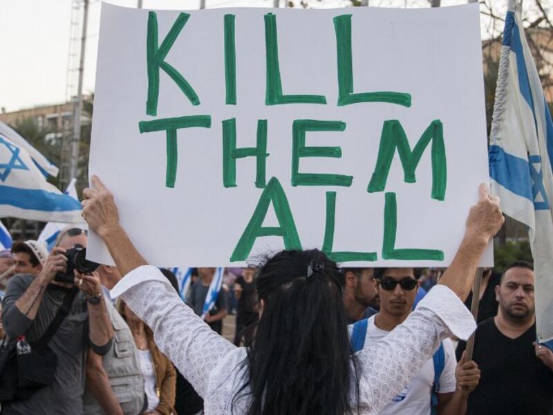An Israeli woman holds up a sign with 'Too many terrorists in prison' on one side and 'Kill them all!' on the other - in reference to Palestinians. (AFP/File)