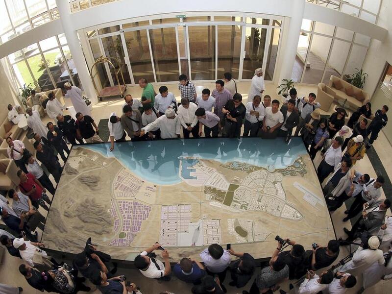A picture taken with a fish-eye lens shows Chinese investors listening to an explanation as they check the model of the dry dock which is to be built following an economic agreement, on May 24, 2016 in the Omani port city of Duqm. Mohammed Mahjoub /AFP Photo
