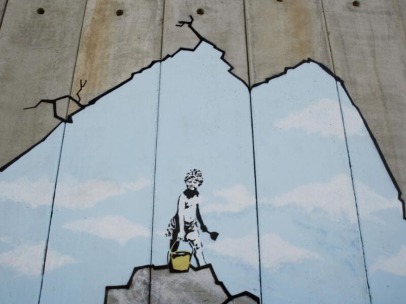 A Palestinian boy play on the beach, drawn on the security barrier in Bethlehem /AFP