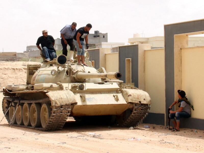 Forces with the National Unity Government stand on a tank in Sirte, Libya, during a land-and-air campaign to retake the city from Daesh. (AFP/Stringer)