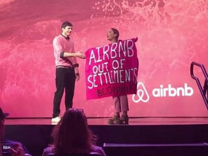 A protester against Airbnb's listing of West Bank settlement rentals during an interview with Ashton Kutcher at Airbnb Open in Los Angeles in 2016. (Screenshot/YouTube)