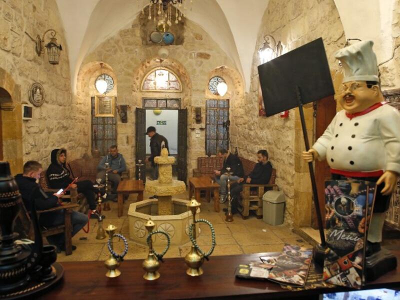 Men smoke waterpipes (shisha or hookah) as they sit at the premises of the first traditional Turkish bath (Hammam) opening in the occupied Palestinian West Bank city of Hebron on March 11, 2019. 
HAZEM BADER / AFP