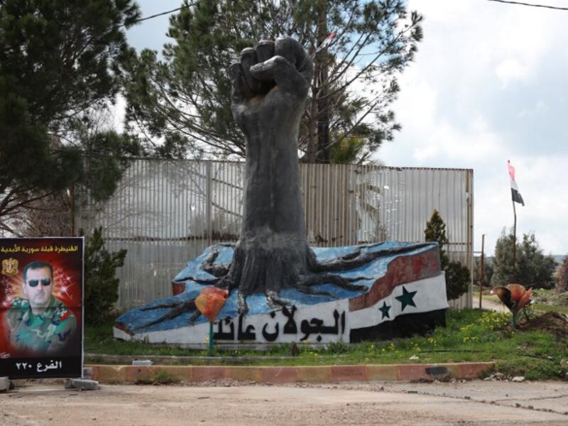A portrait of the Syrian President Bashar al-Assad stands near a sculpture in the Syrian town of Quneitra, in the Golan Heights on March 26, 2019. The writing in Arabic reads: "The Golan is ours". 
Louai Beshara / AFP