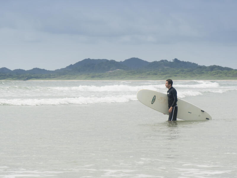 Young man going to surf in Tamarindo, Costa Rica. Tamarindo is located on the Northern Pacific Coast and a leading surfer hotspot. (Shutterstock)