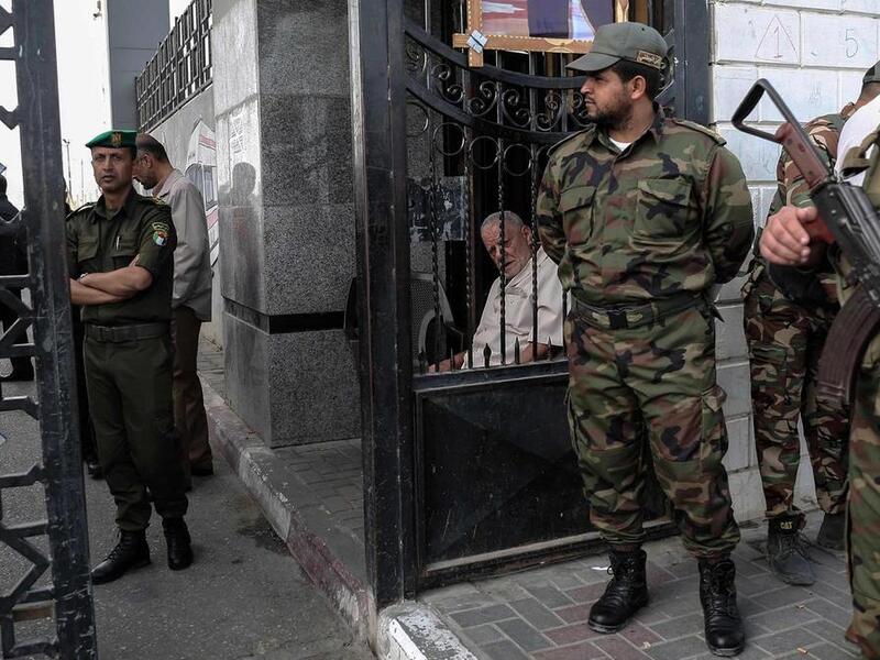 Palestinian security forces loyal to Hamas (right) stand guard outside the Rafah border crossing with Egypt, as security forces loyal to the Palestinian Authority stand guard inside (left), in the southern Gaza Strip. 
Said Khatib / AFP
