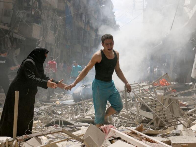 People walk amid the rubble of destroyed buildings following a reported air strike on the rebel-held area of Aleppo. (AFP/File)