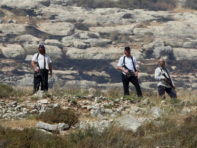 Armed settlers overlook a Palestinian village south of Nablus during confrontations following the setting on fire of Palestinian-owned fields on Jan. 1, 2010. (AFP/Jaafar Ashtiyeh)