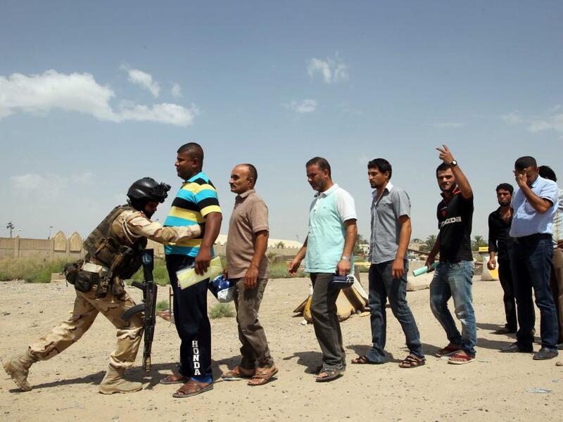 An Iraqi soldier bodychecks men in Baghdad as they arrive to volunteer to join the fight against a major offensive by jihadists in northern Iraq on June 13, 2014. Iraqi forces have clashed with militants advancing on the city of Baquba, just 60 kilometres north of Baghdad. (AFP/Ali Al Saadi)
