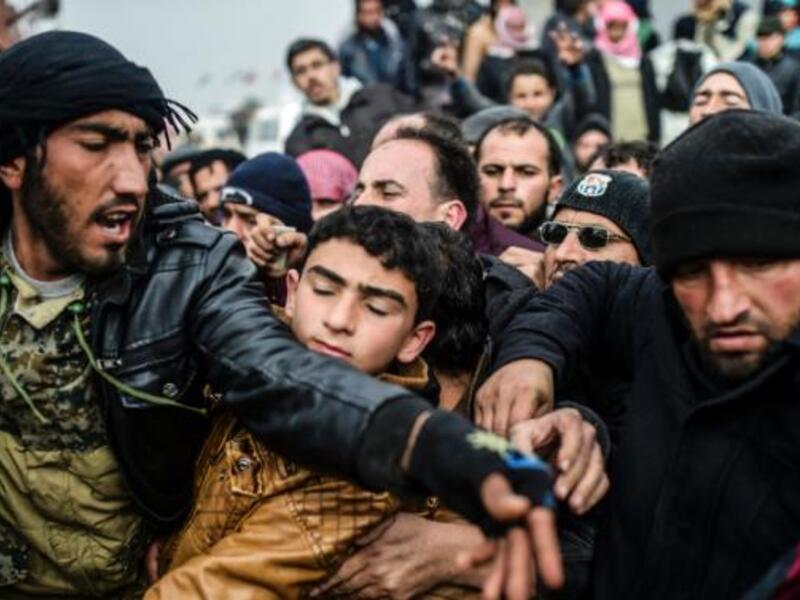 Syrian refugees jostle each other near the Turkish border crossing on February 6, 2016. (AFP/File)