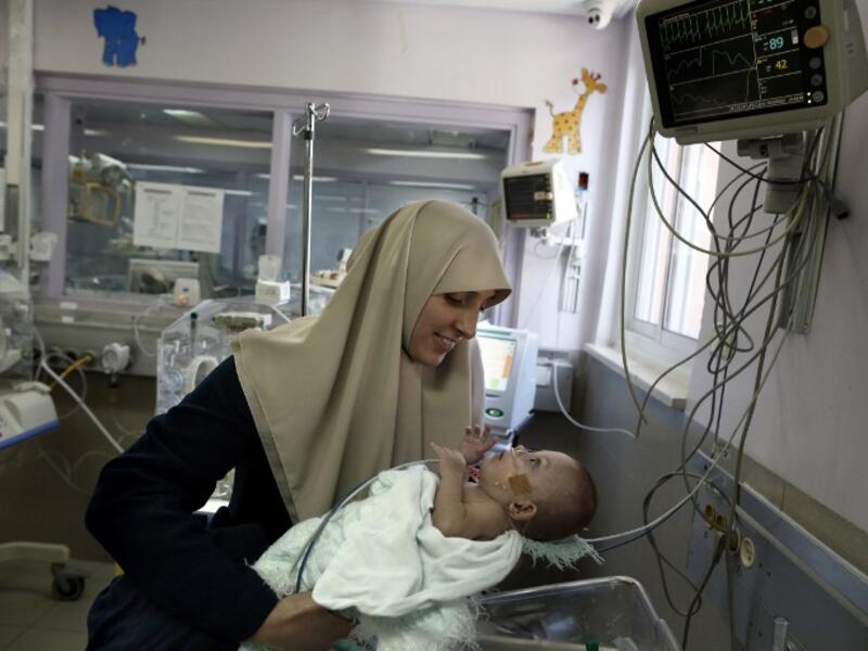 Gazan Jumana Daoud carries her 7-month-old daughter Maryam at Makassed Hospital in East Jerusalem on February 20, 2017 as they meet for the first time since the baby’s premature birth. [AFP/Ahmad Gharabli]