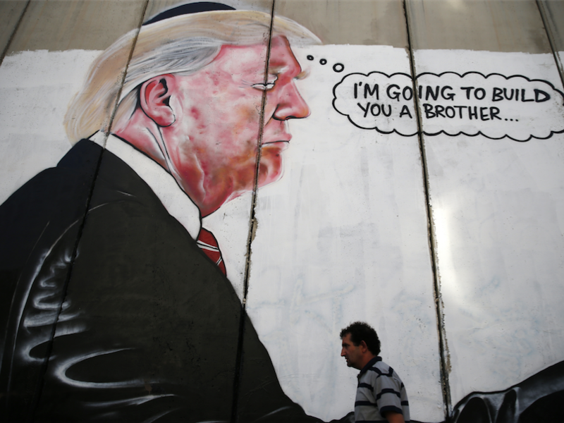 A Palestinian man walks past graffiti depicting US President Donald Trump on the controversial Israeli separation wall in the West Bank town of Bethlehem. (AFP) 