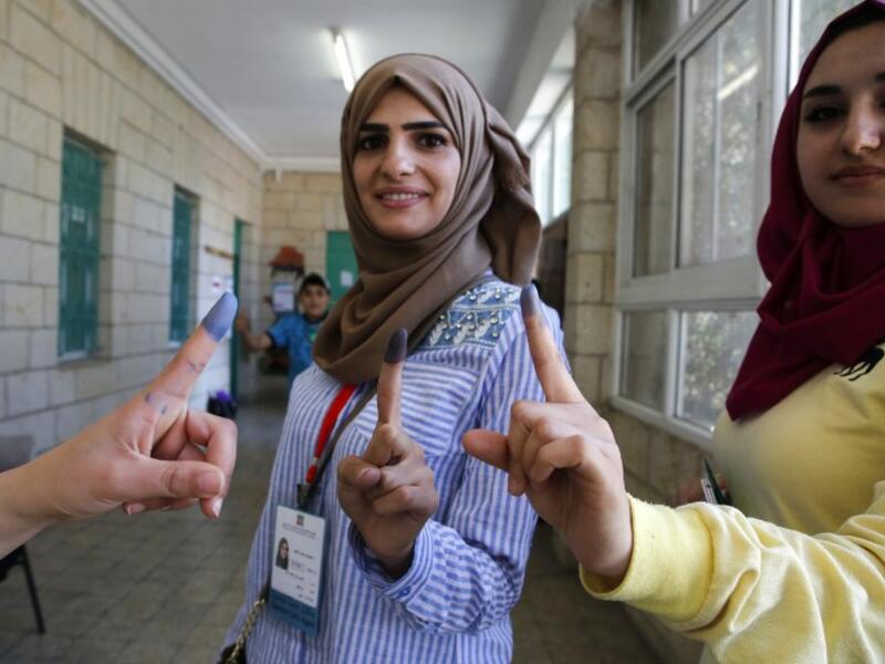 Palestinian women show their ink-stained fingers after casting their ballots during the municipal elections in the West Bank city of Ramallah on May 13, 2017. (AFP/Abbas Momani)