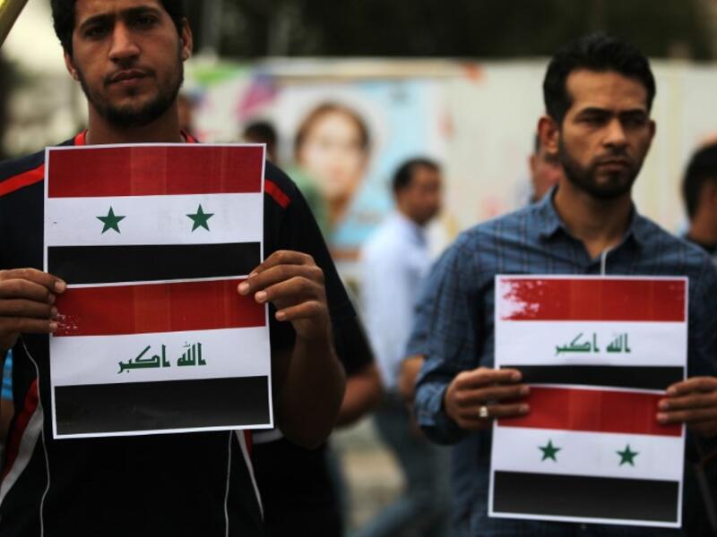 Two protestors display Syrian and Iraqi flags down Baghdad’s Tahir Region on April 15, 2017, AHMAD AL-RUBAYE / AFP