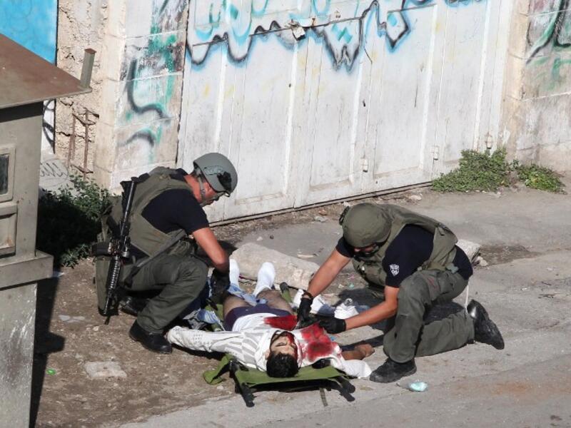 Israeli security forces inspect the body of a Palestinian man who stabbed and lightly wounded an Israeli border guard before being shot dead in the Israeli occupied West Bank city of Hebron, on October 29, 2015. (AFP / Hazem Bader)  