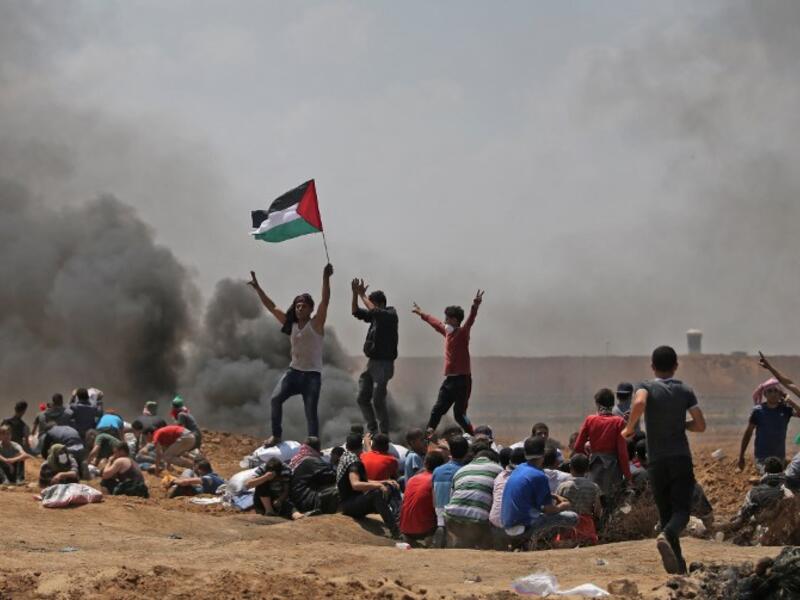 Palestinians wave their national flag as they demonstrate near the border between Israel and the Gaza Strip /AFP