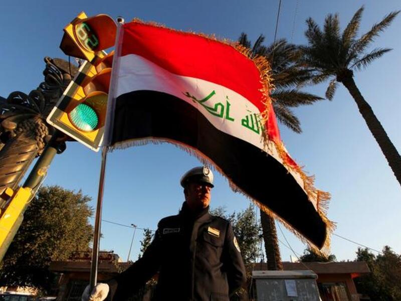 شرطي عراقي يحمل العلم في الشارع