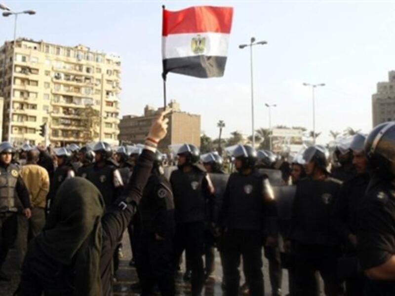 An Egyptian demonstrator holds up her national flag near the Egyptian police.
