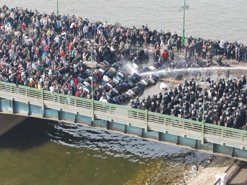 The first tumultuous Friday prayers: supplicating Muslims at prayer take the full force of the water guns on the front line, cushioning  their fellow compatriots.