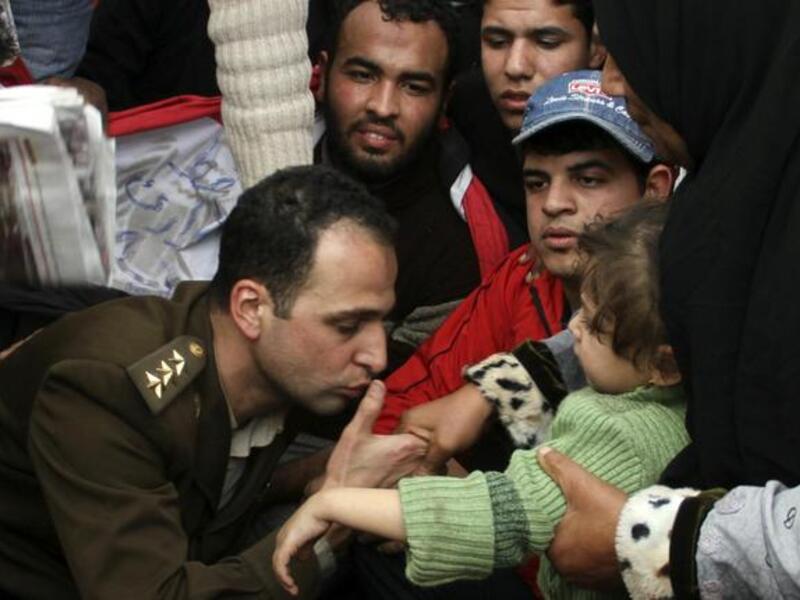 An Egyptian officer shows his position of solidarity with his people by a kiss to a child in the arms of its mother.