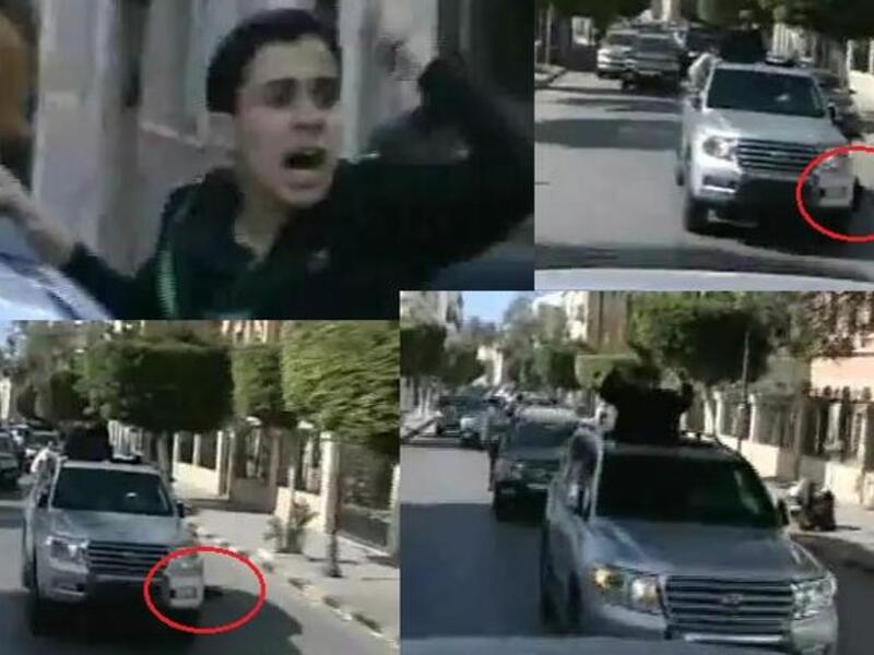 Fist-air-punching Gaddafi on his latest public outing:– his boy supporter falls flat from the Gaddafi-car-mobile, and Gaddafi only momentarily glances at him before carrying on thumping the air, unfazed.