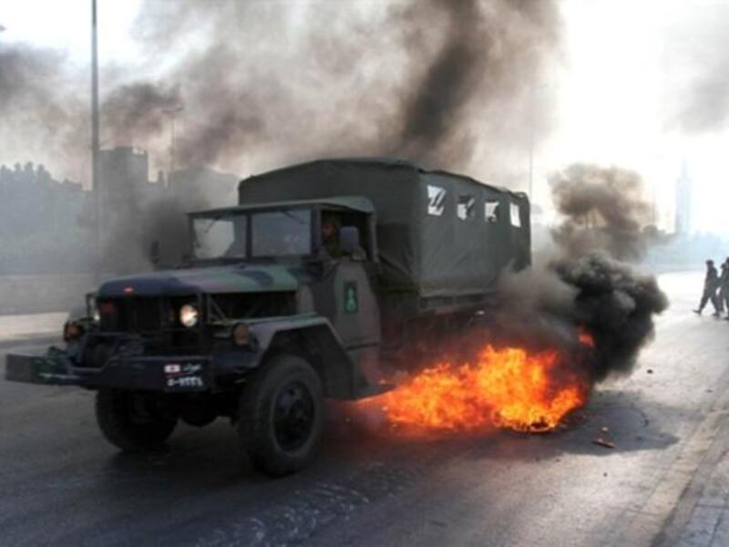 A Lebanese army truck drives through burning tires.